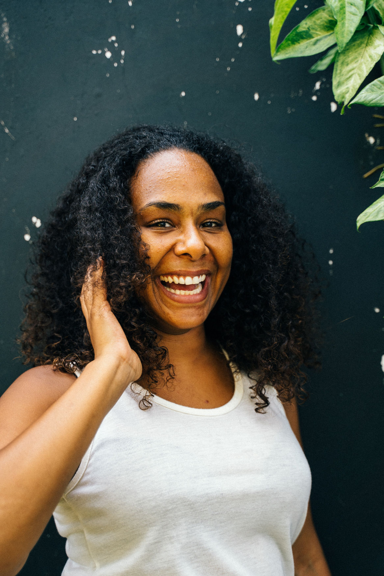 A smiling woman with curly hair against a deep green backdrop